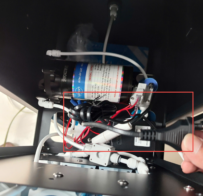 A hand holding a cable to a machine

Description automatically generated