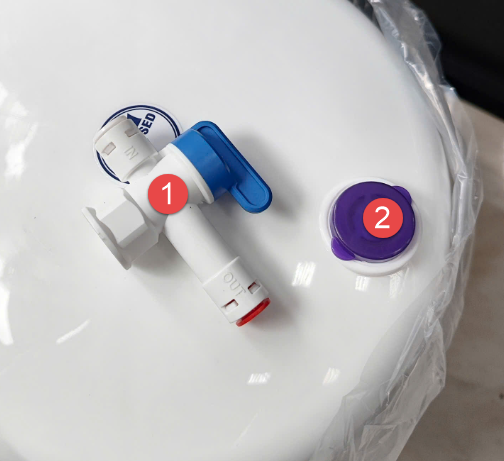 A white toilet with a plastic bag and a blue and white valve

Description automatically generated with medium confidence